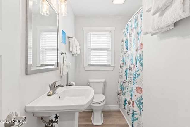 bathroom with shower / bathtub combination with curtain, hardwood / wood-style flooring, and toilet