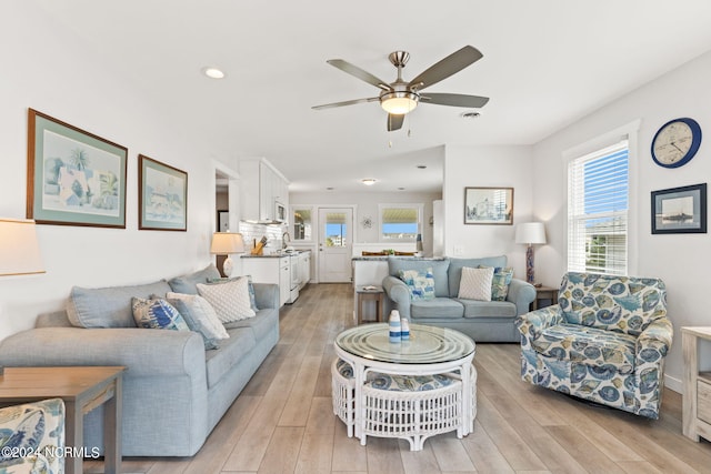 living room with sink, ceiling fan, and light wood-type flooring