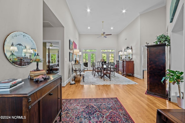 foyer entrance with ceiling fan, ornamental molding, light wood-type flooring, and a towering ceiling