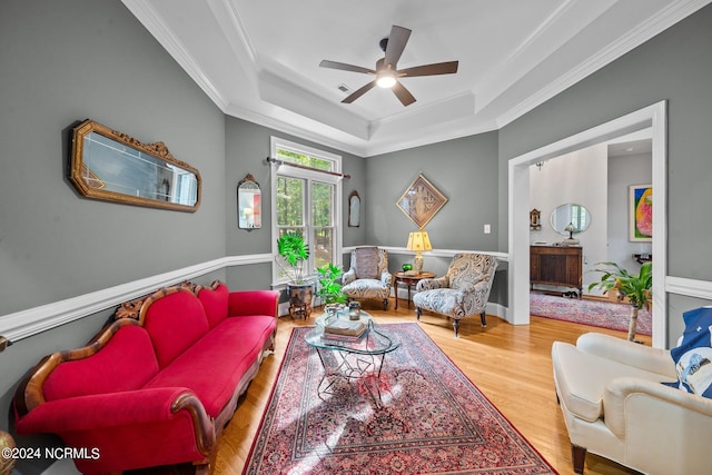 living room featuring ceiling fan, hardwood / wood-style flooring, a raised ceiling, and crown molding