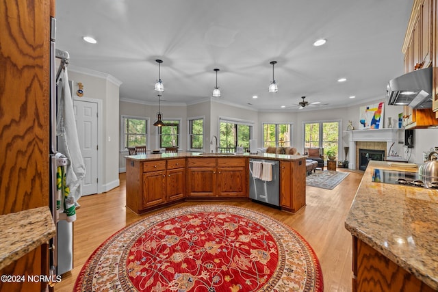 kitchen featuring ventilation hood, a tile fireplace, ceiling fan, pendant lighting, and stainless steel dishwasher