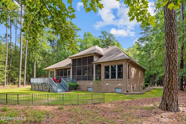 rear view of property with a lawn, a wooden deck, and a sunroom