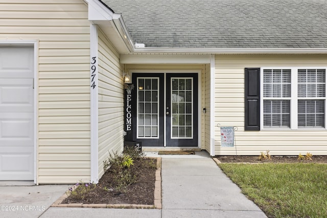 entrance to property featuring french doors, roof with shingles, and an attached garage