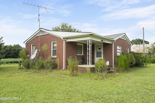 view of front facade with a front yard, brick siding, and covered porch