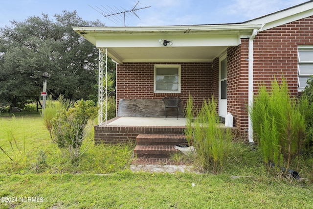 property entrance featuring brick siding and covered porch