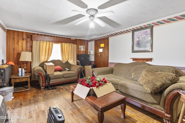 living room featuring wooden walls, wood-type flooring, and a ceiling fan