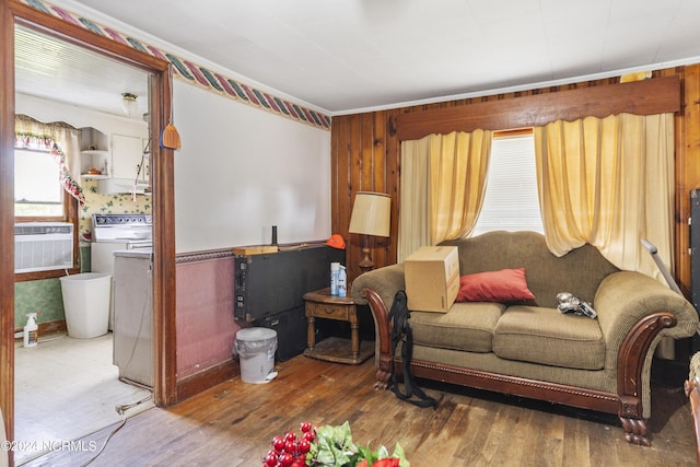 living area with wood walls, wood finished floors, a wall unit AC, and washer / dryer
