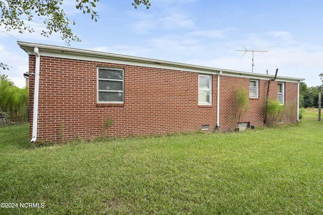 view of side of property featuring a yard, brick siding, and crawl space