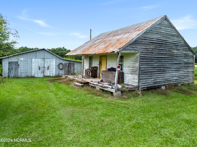 back of property featuring a lawn and an outbuilding