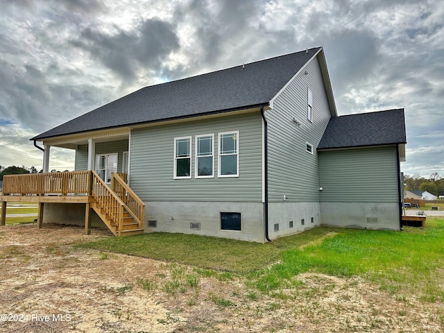 rear view of property with a wooden deck and a yard