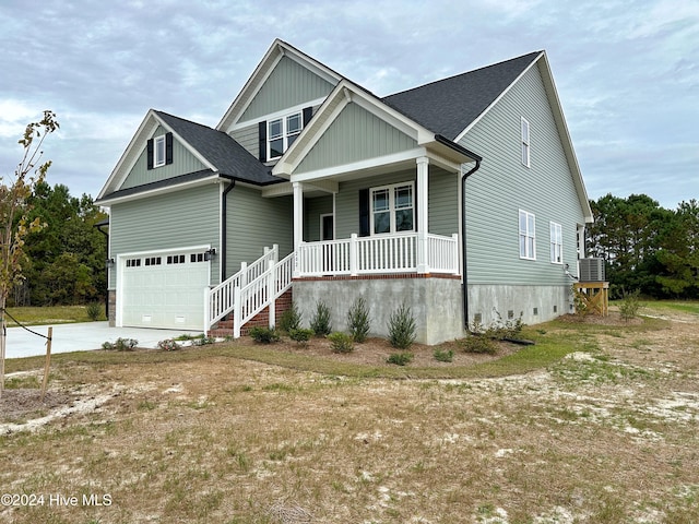 view of front of property featuring central air condition unit, covered porch, and a garage