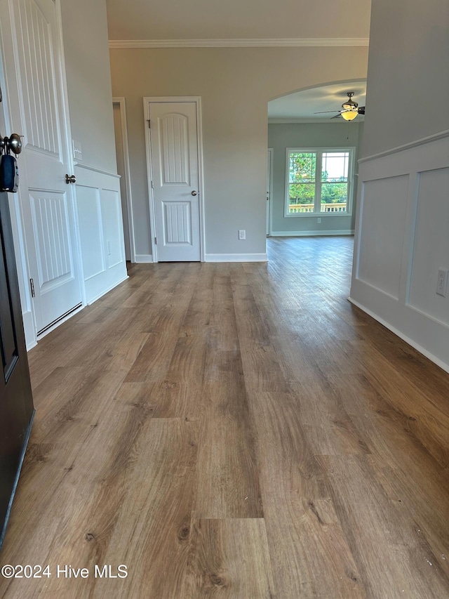 empty room with ceiling fan, light hardwood / wood-style flooring, and crown molding