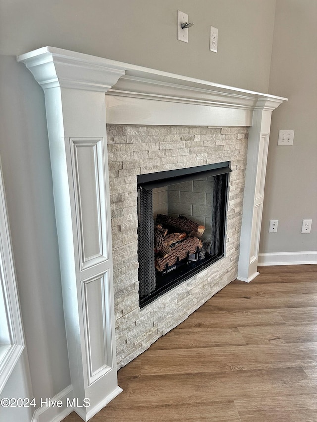 interior details with a stone fireplace and hardwood / wood-style flooring