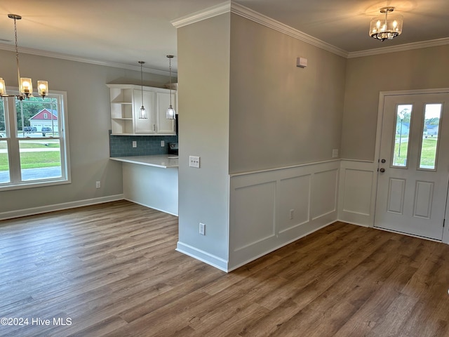 foyer entrance featuring hardwood / wood-style flooring, an inviting chandelier, and ornamental molding