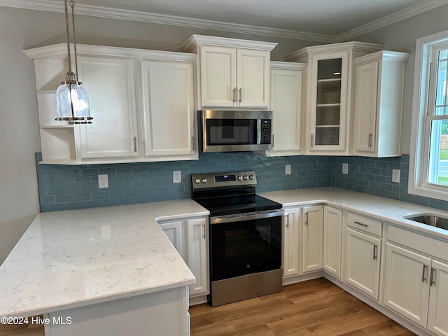 kitchen with white cabinets, crown molding, stainless steel appliances, and light hardwood / wood-style flooring