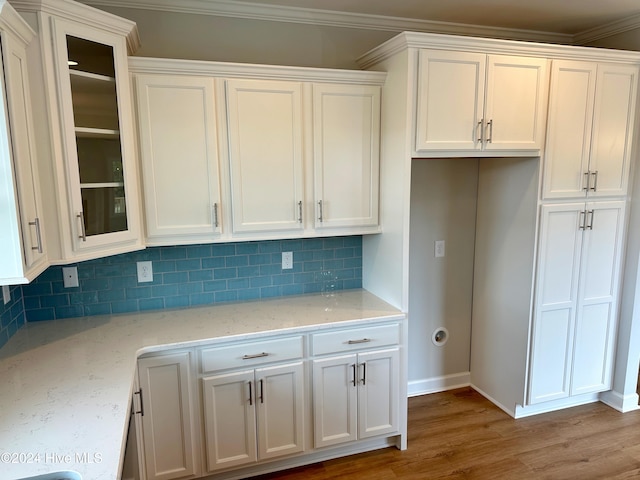 kitchen with light stone countertops, hardwood / wood-style floors, white cabinetry, and crown molding