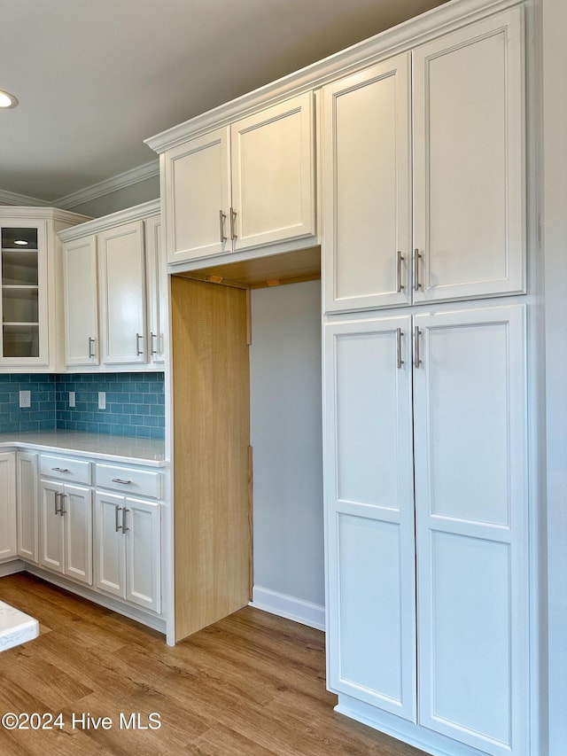 kitchen featuring white cabinetry, crown molding, and light hardwood / wood-style floors