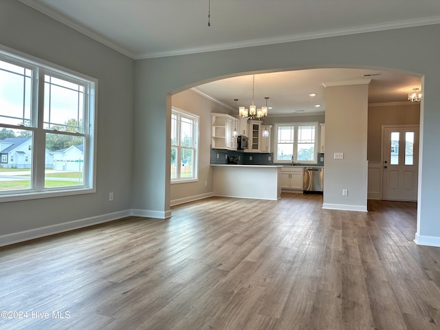 unfurnished living room with light wood-type flooring, a wealth of natural light, ornamental molding, and sink