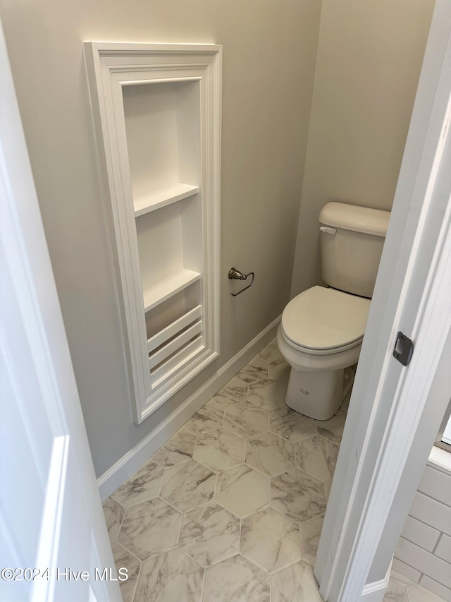 bathroom featuring built in shelves and toilet