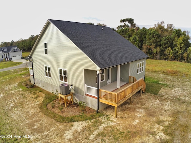 back of property with a lawn, covered porch, and central AC