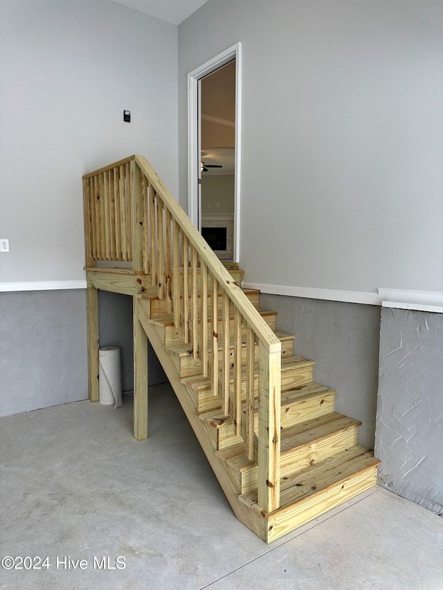 staircase with ceiling fan and concrete flooring