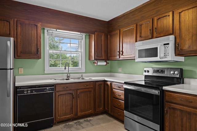 kitchen featuring appliances with stainless steel finishes, light tile patterned flooring, and sink