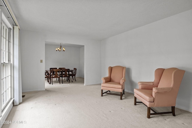 living area with a textured ceiling, an inviting chandelier, and carpet floors