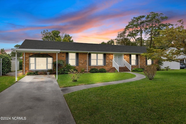 ranch-style house with a yard, driveway, and brick siding