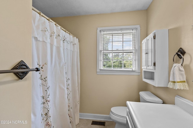 bathroom featuring a textured ceiling, vanity, toilet, and walk in shower