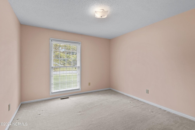 carpeted spare room with a textured ceiling