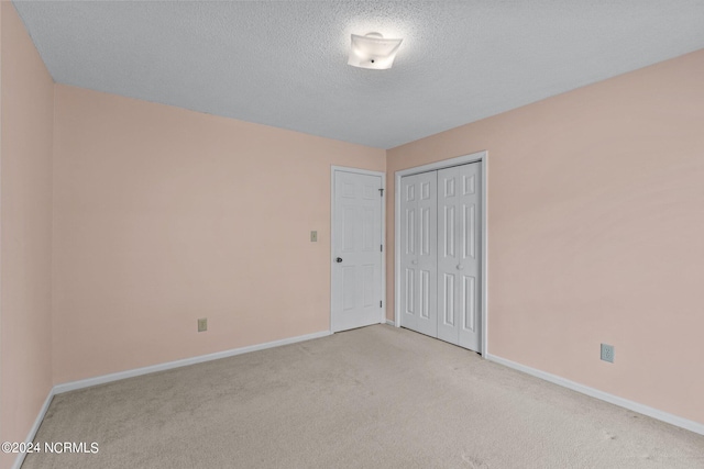 unfurnished bedroom with light carpet, a textured ceiling, and a closet