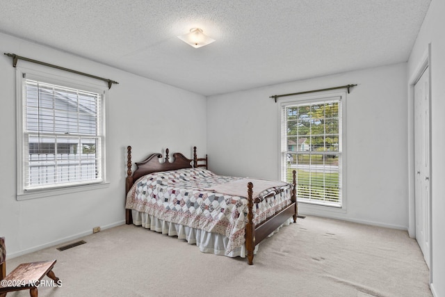 bedroom featuring a textured ceiling, light colored carpet, and a closet