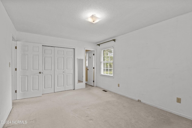 unfurnished bedroom with a textured ceiling, a closet, and light carpet