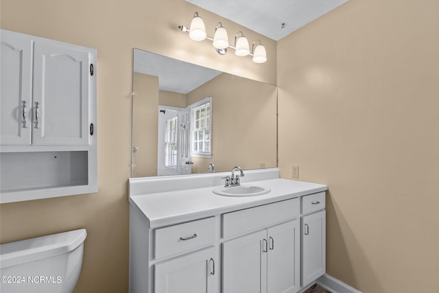 bathroom with vanity, toilet, and a textured ceiling