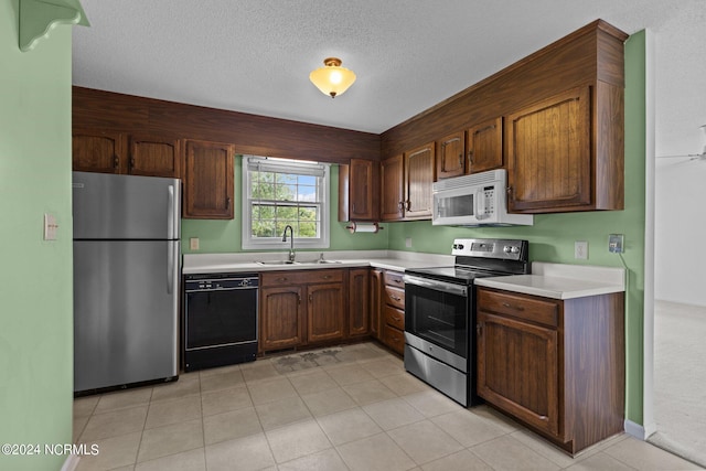 kitchen featuring appliances with stainless steel finishes, a textured ceiling, light tile patterned floors, and sink