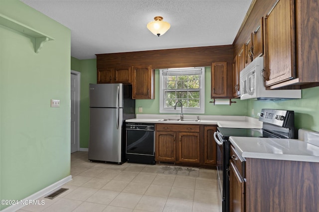 kitchen featuring stainless steel appliances, a textured ceiling, light tile patterned flooring, and sink