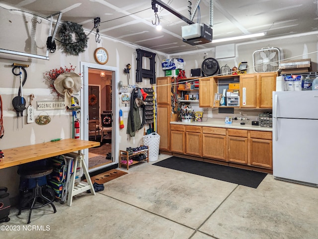 garage with white refrigerator, a workshop area, and a garage door opener