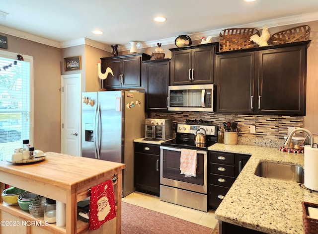 kitchen featuring light tile patterned floors, light stone countertops, stainless steel appliances, sink, and ornamental molding