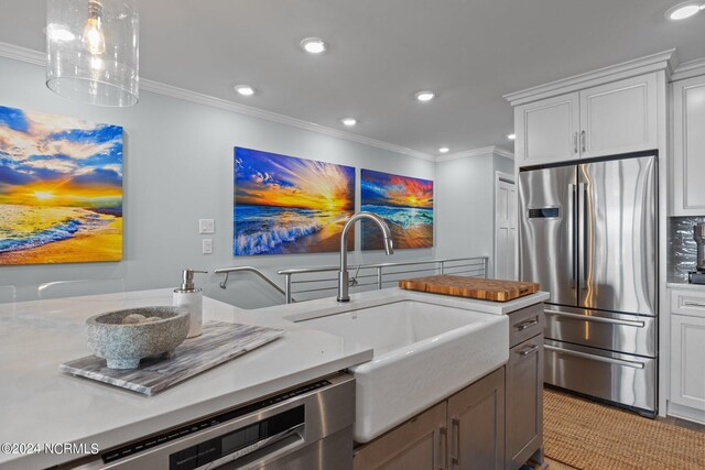 kitchen with appliances with stainless steel finishes, crown molding, white cabinetry, and sink