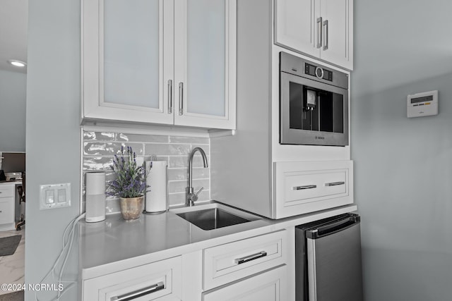 kitchen with appliances with stainless steel finishes, tasteful backsplash, white cabinetry, and sink