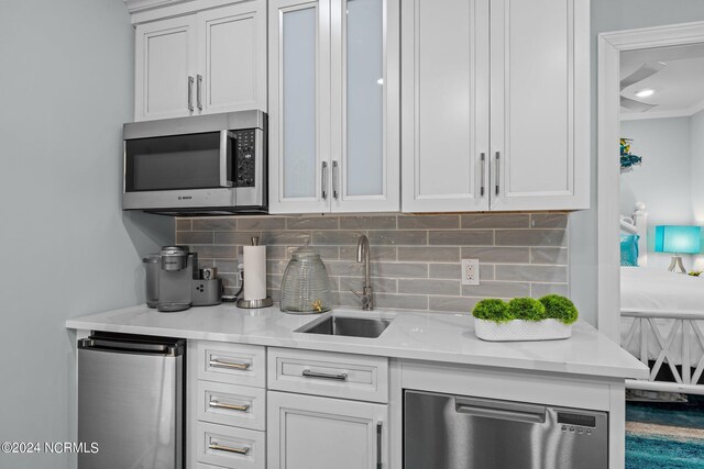 kitchen with tasteful backsplash, light stone counters, sink, and white cabinets