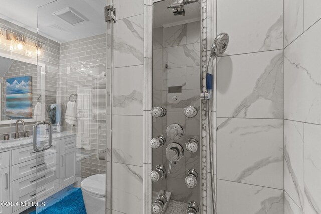 bathroom featuring vanity, toilet, tile walls, and walk in shower