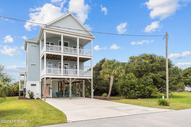 raised beach house featuring a carport, covered porch, a balcony, and a front yard