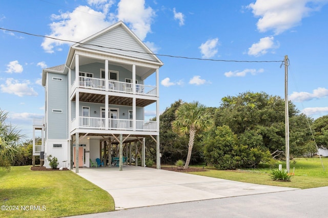 raised beach house with a front lawn, a carport, driveway, and a balcony