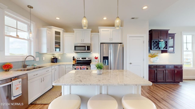 kitchen featuring tasteful backsplash, a sink, appliances with stainless steel finishes, visible vents, and decorative light fixtures
