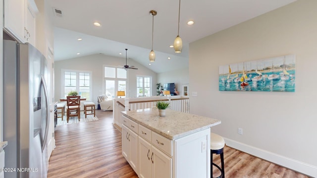 kitchen with vaulted ceiling, ceiling fan, a kitchen bar, stainless steel refrigerator with ice dispenser, and open floor plan