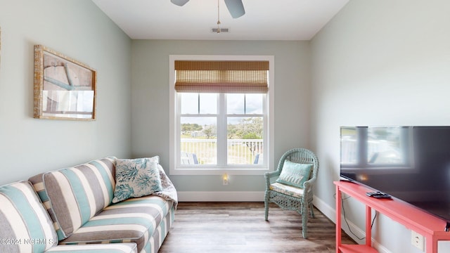 living area with wood finished floors, visible vents, ceiling fan, and baseboards