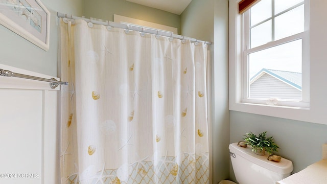 bathroom featuring toilet and curtained shower