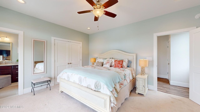 carpeted bedroom with ensuite bath, ceiling fan, and a closet