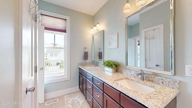 bathroom featuring a sink, tile patterned floors, double vanity, visible vents, and baseboards